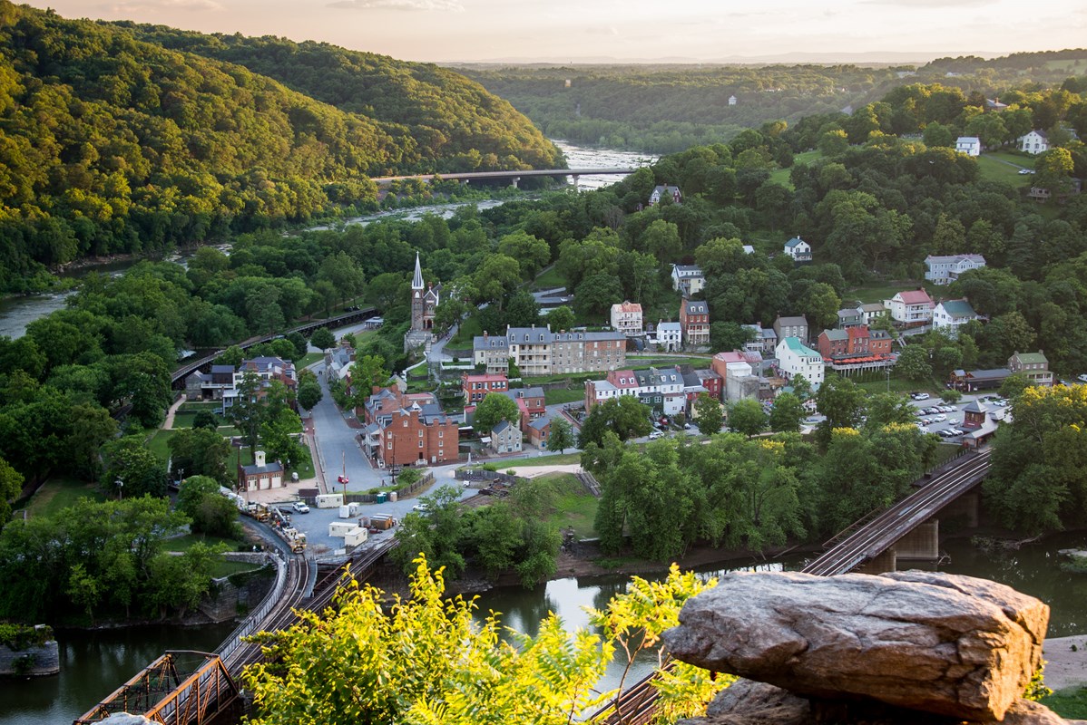 Harpers Ferry, river bridges, and green hills in warm evening light